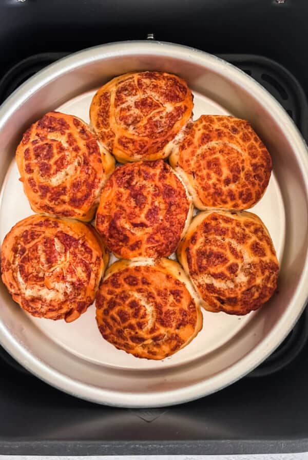 Cinnamon rolls in the basket of the air fryer, ready to top with glaze and serve.