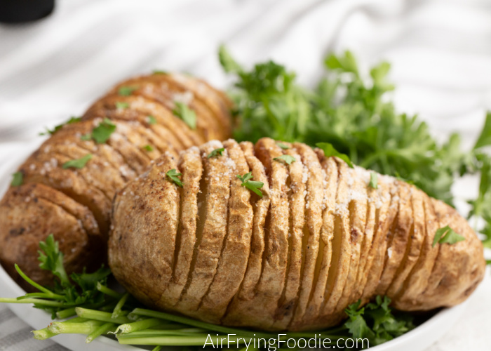 Air Fried Hasselback Potatoes on a white plate with fresh parsley. 