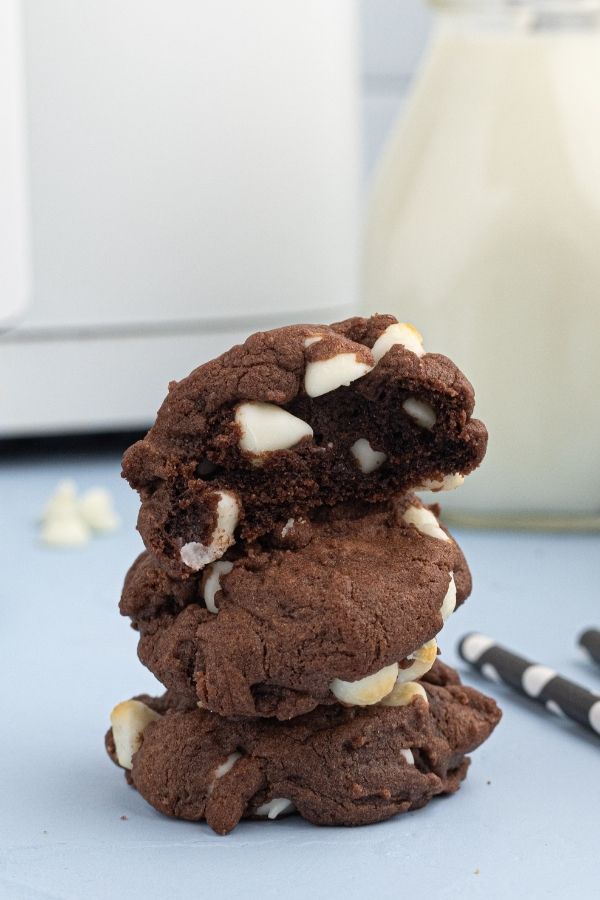 Moist chocolate cookies with white chips, stacked, with the top cookie showing a bite missing. 