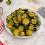 Cooked parmesan brussel sprouts, served on a white plate.