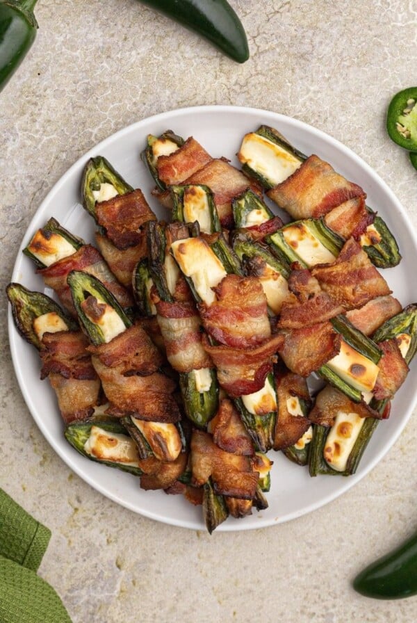 Air Fryer Jalepeno Poppers stuffed with cream cheese and wrapped in bacon, serve on a white plate