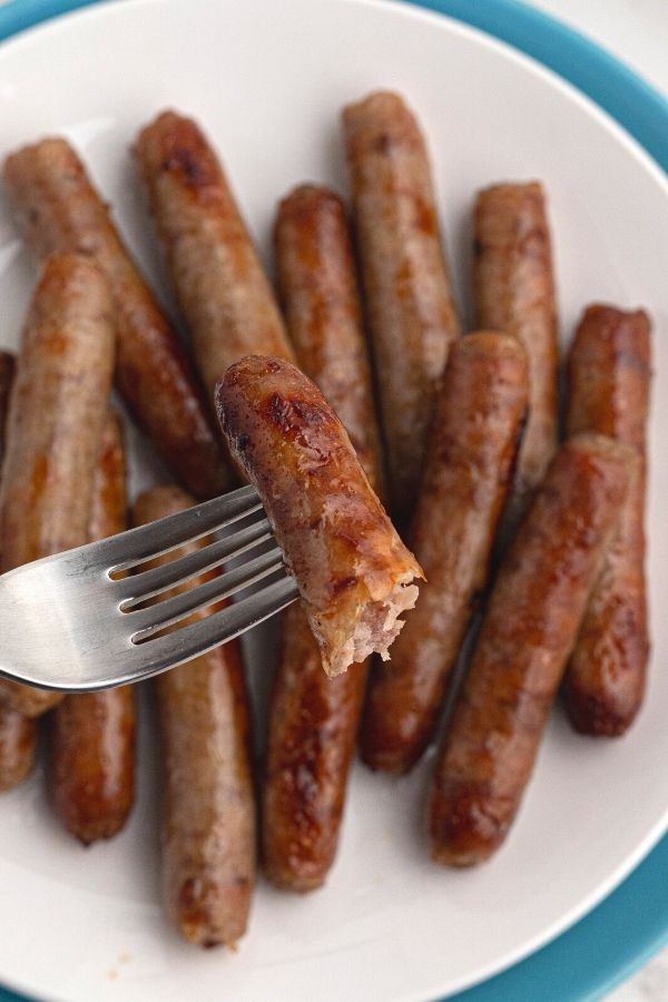 Cooked sausage with a piece on the fork, showing doneness of cooking. 