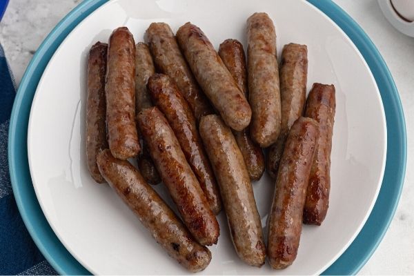 Cooked juicy sausage links, served on a white plate. 