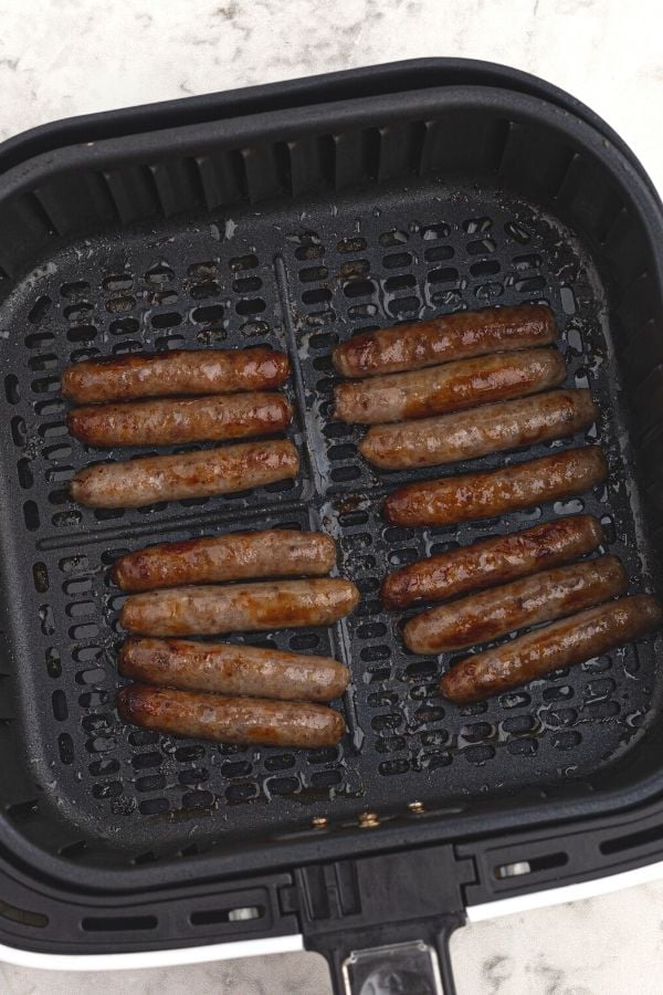 Cooked and crispy sausage in an air fryer basket. 
