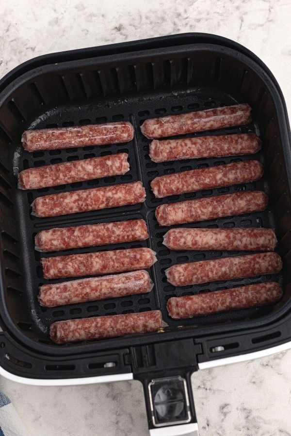 Uncooked sausage links placed in the air fryer basket.
