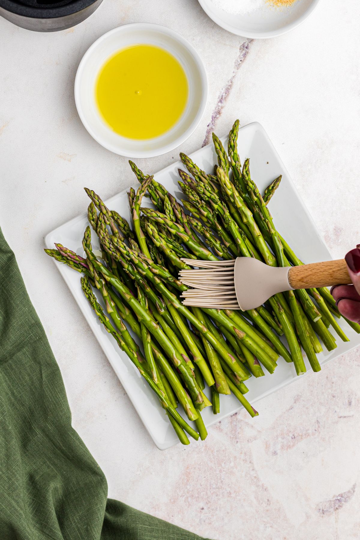 Asparagus being brushed with olive oil