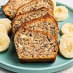 Golden moist bread sliced on a light green plate with slices of bananas.