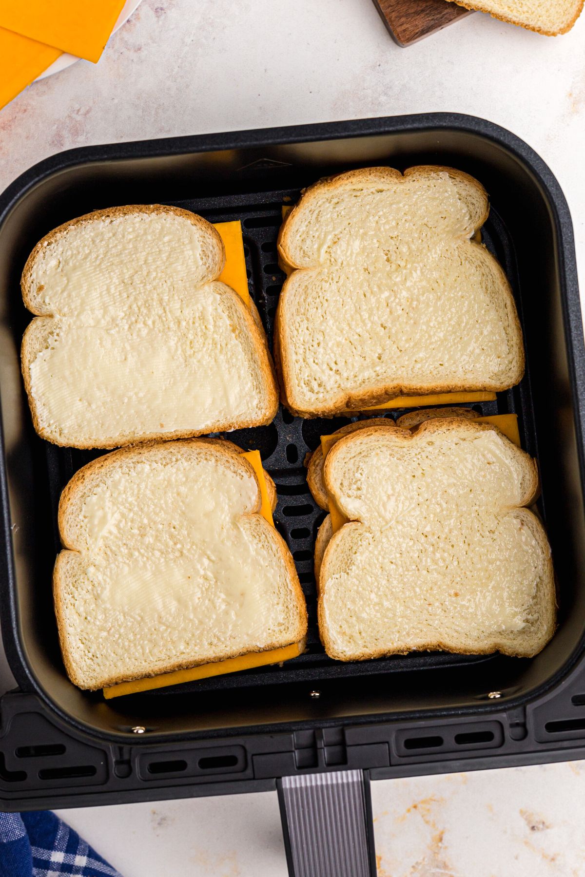 bread slices filled with cheese in the air fryer basket before being cooked