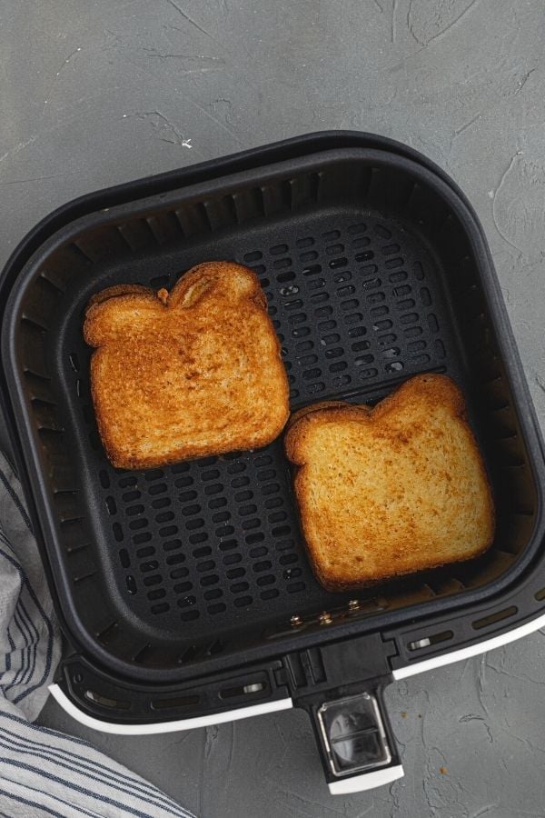 Cooked grilled cheese sandwiches in the air fryer basket.