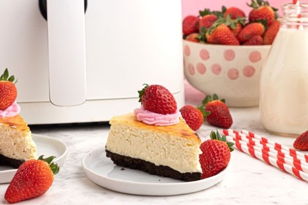 Cooked creamy cheesecake with a chocolate cookie crust, topped with strawberries.