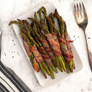 Crispy bacon wrapped asparagus served on a white plate
