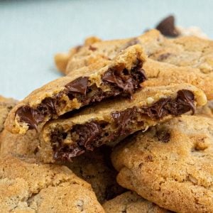 Close up photo of chocolate chip cookies with melting chocolate dripping out of cookie.
