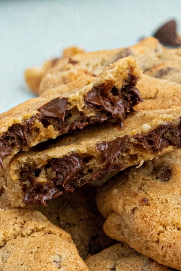 Close up photo of chocolate chip cookies with melting chocolate dripping out of cookie.