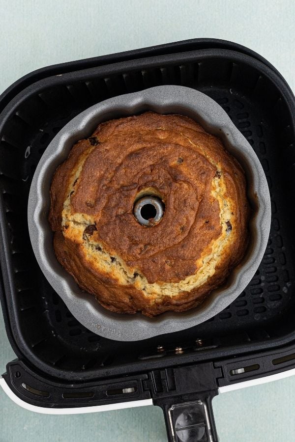 Cooked chocolate chip pound cake dough in a bundt cake pan set in an air fryer basket. 