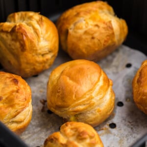 Air Fryer Biscuit Bombs on parchment paper in the basket of the Air Fryer.