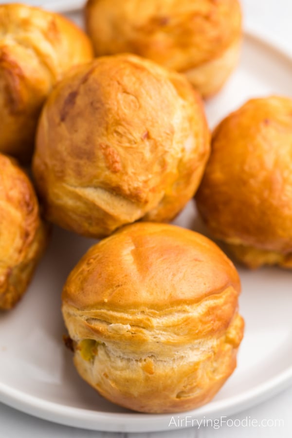 Biscuit Bombs stuffed with cheese, egg, and bacon on a white plate. 