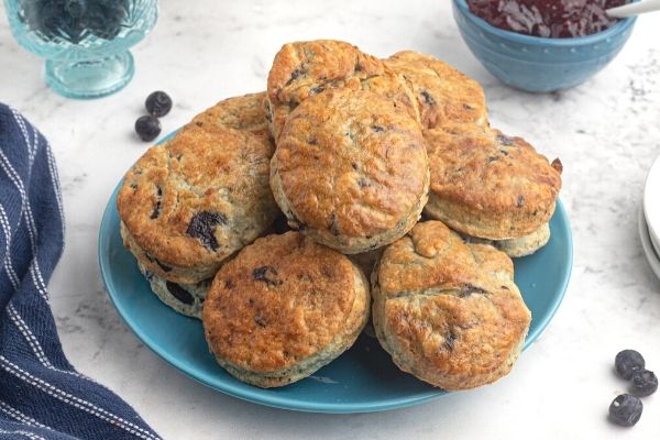 Air fryer blueberry scones on a light blue plate, with scattered blueberries around the plate. 