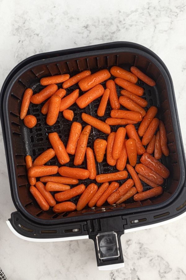 Uncooked honey glazed baby carrots in the air fryer basket. 