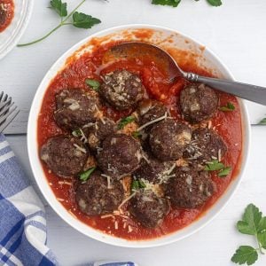 Air fryer meatballs served in a red sauce, topped with parmesan cheese and parsley garnish.