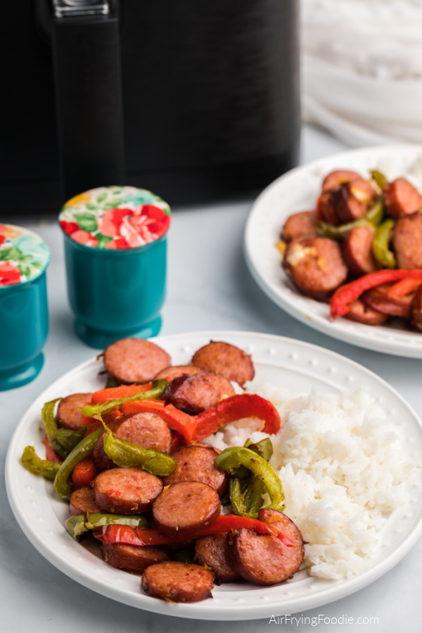 Sausage and peppers on a white plate served with rice. 