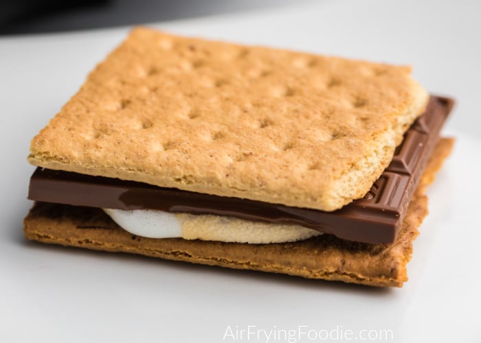 S'more made with graham cracker, chocolate, and marshmallow on a white plate. 