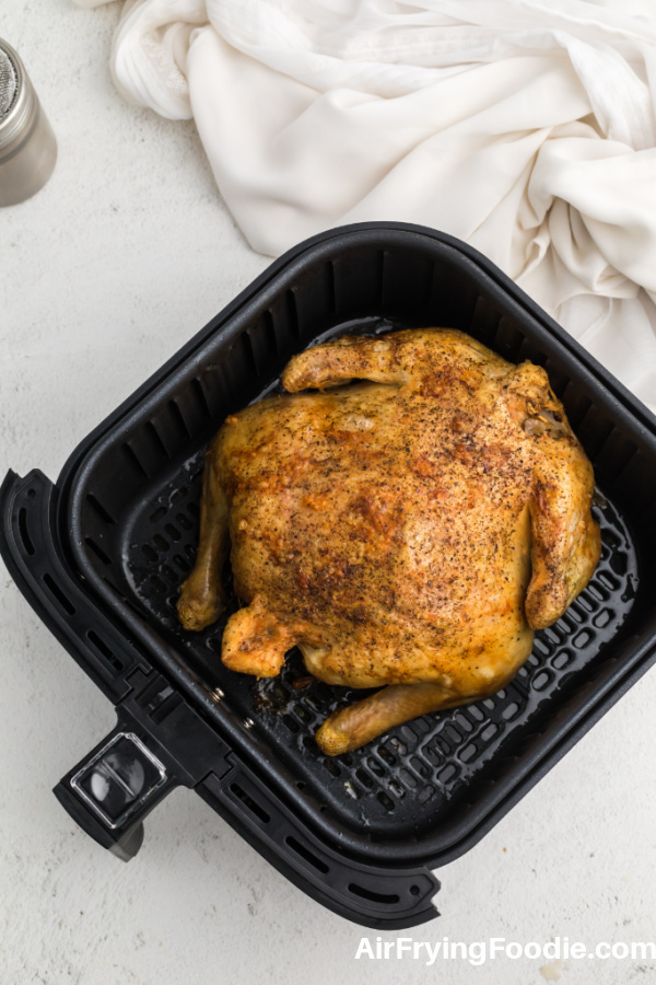 Fully cooked Whole chicken in Air Fryer basket. 