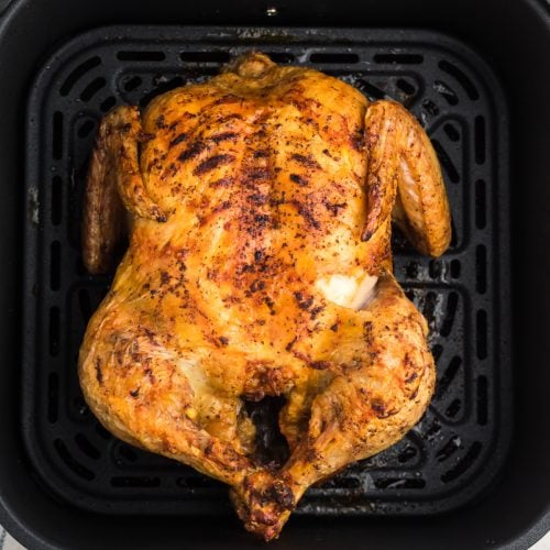 Air fryer whole chicken fully cooked and in the basket of the air fryer.
