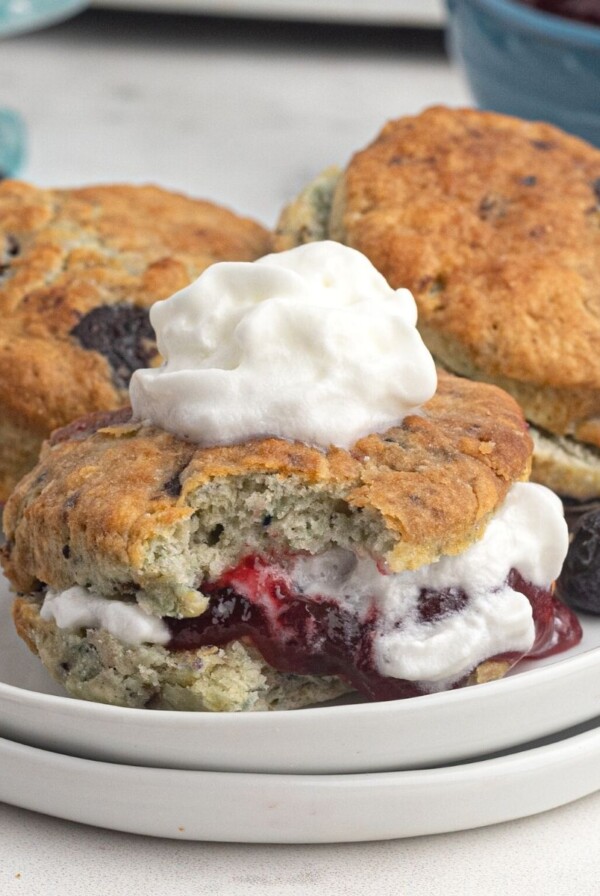 Air fryer blueberry scones, filled with jam and cream, served on a white plate.