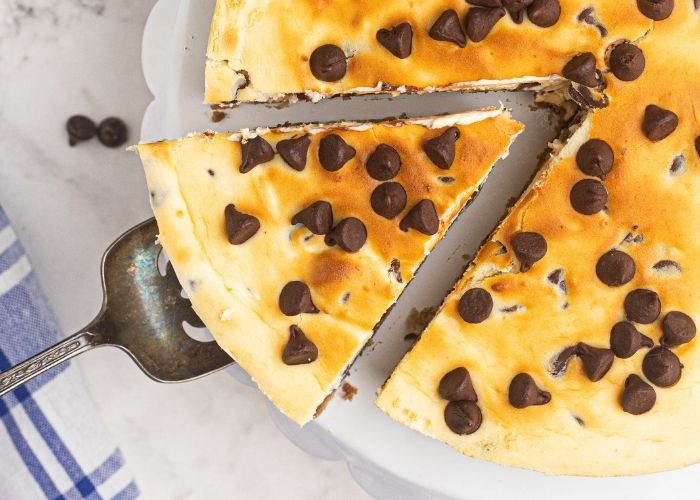 Creamy chocolate chip cheesecake sliced and being served on a spatula.