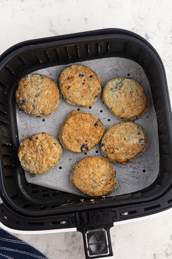 Cooked air fryer blueberry scones in an air fryer basket. 