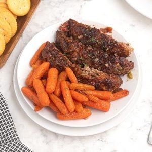 Honey Glazed Carrots served on a white plate next to meatloaf.