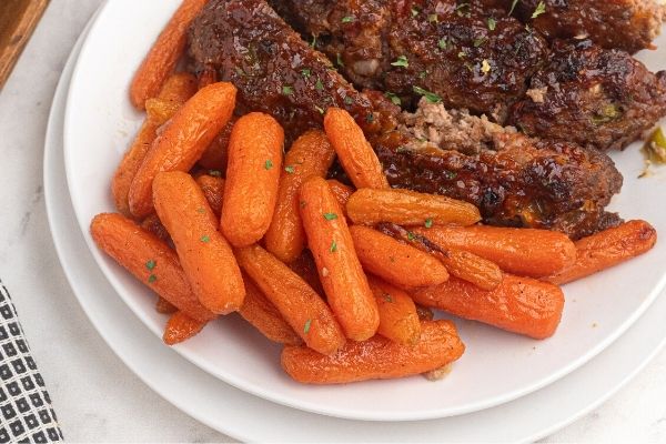 Air Fryer Honey Glazed carrots served on a white plate with meatloaf sliced.
