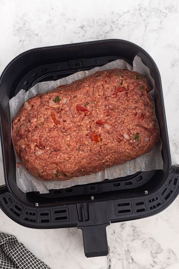 Uncooked meatloaf in the air fryer basket. 