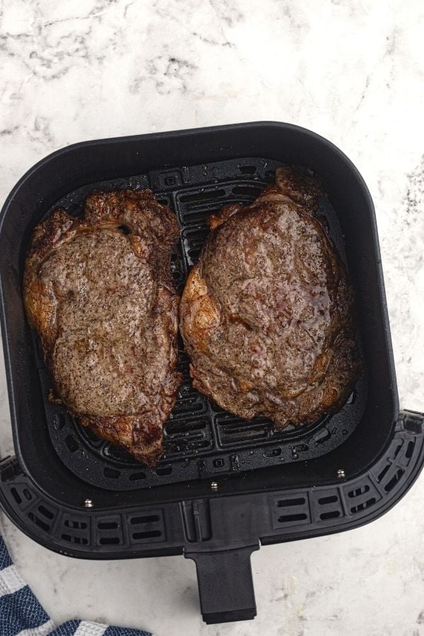 Juicy and thick ribeye steaks, cooked in an air fryer basket. 