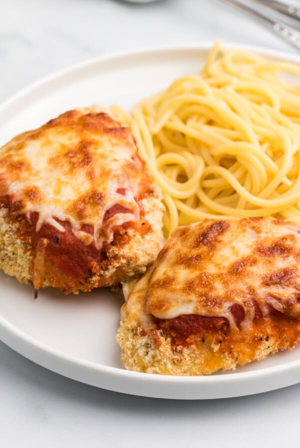 Air Fryer chicken parmesan on a white plate with spaghetti noodles.