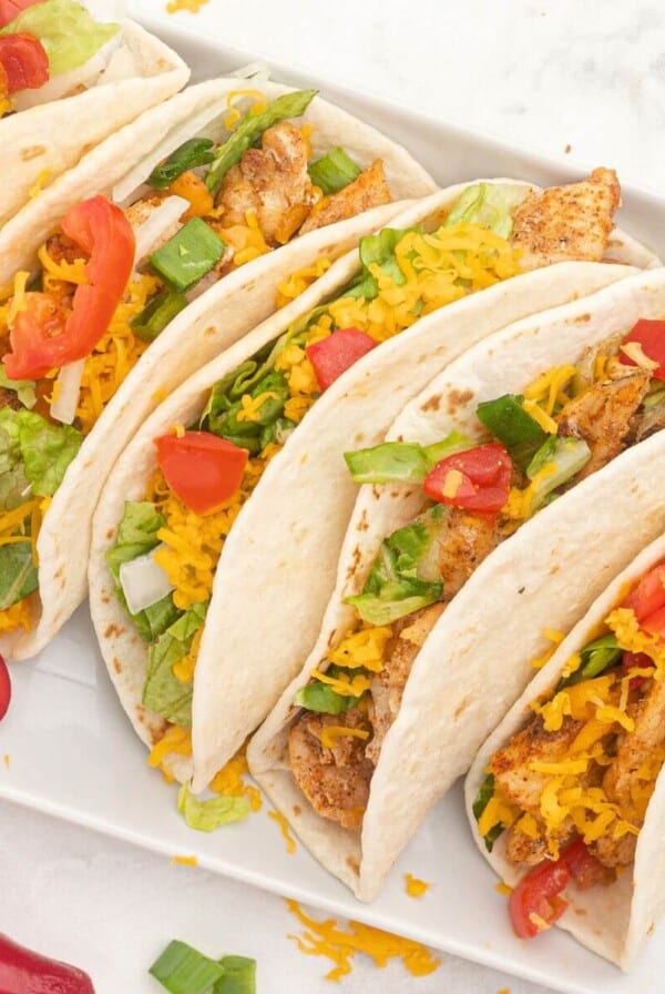 Seasoned chicken in flour tortillas topped with shredded cheese and chopped tomatoes and peppers.