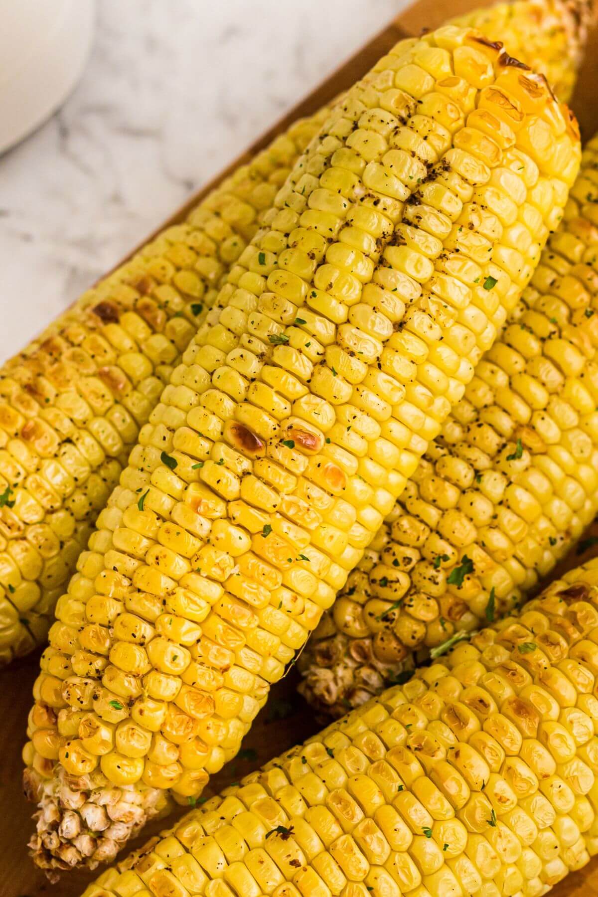 golden yellow ears of corn seasoned on a cutting board. 