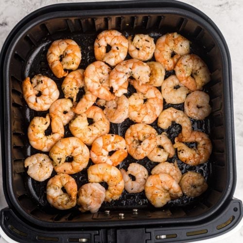 Garlic butter shrimp in the air fryer basket after being cooked.