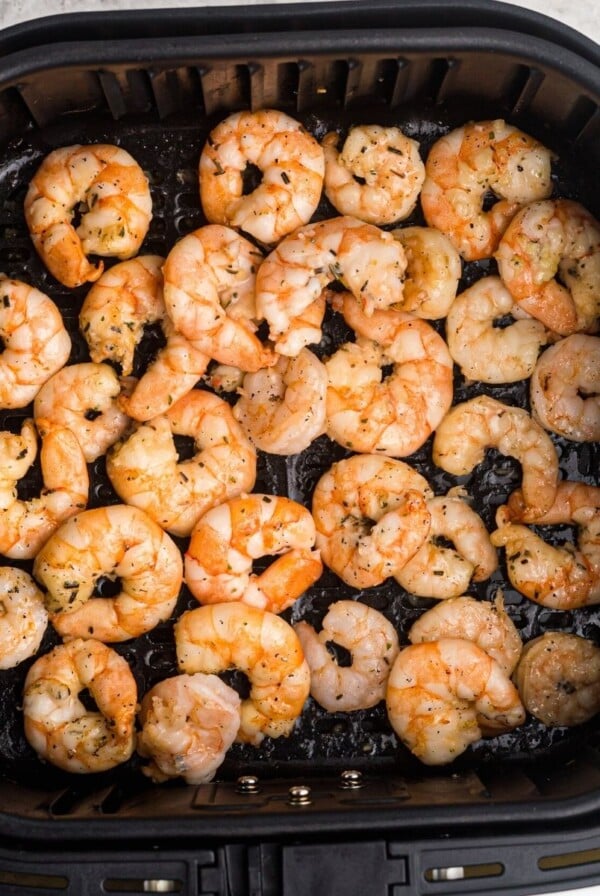 Garlic butter shrimp in the air fryer basket after being cooked.