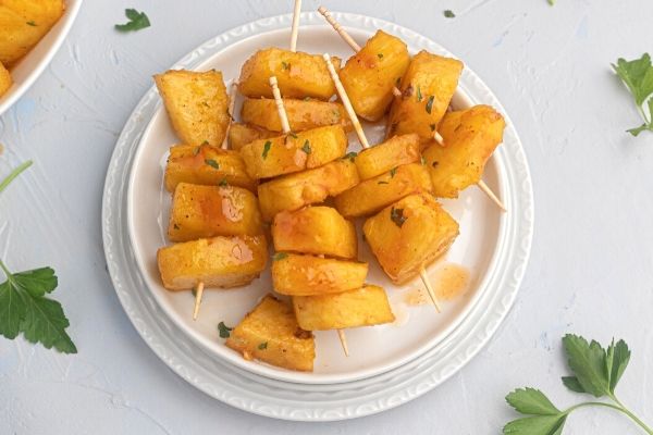 Juicy glazed pineapple served on a white plate. 