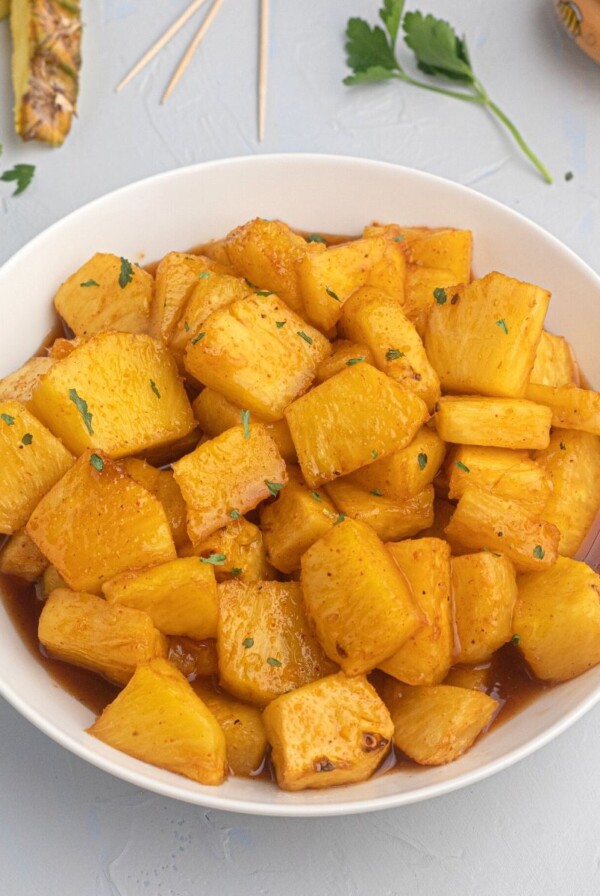 Juicy pineapple glazed with honey and bbq sauce, served in a white bowl.