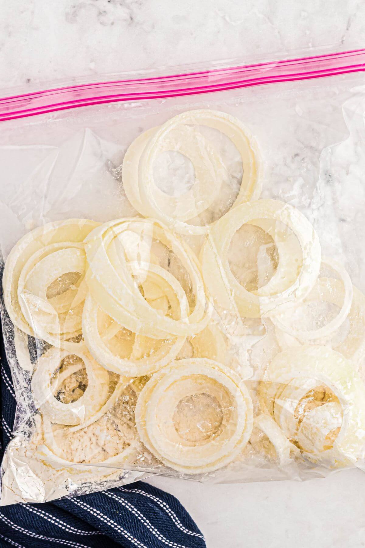 Onions sliced in a ziploc bag being mixed with flour.