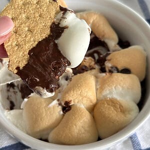 S'mores dip made in the air fryer, with a graham cracker being dipped into the chocolate and marshmallow before eating.