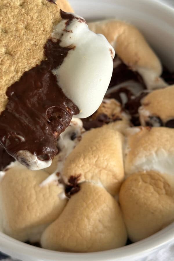 S'mores dip made in the air fryer, with a graham cracker being dipped into the chocolate and marshmallow before eating.