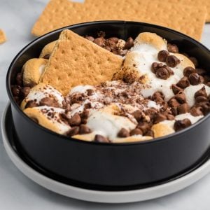 S'mores Dip in a springform pan with a graham cracker in the middle for serving.