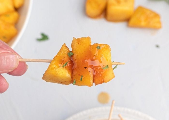 Juicy glazed pineapple on a toothpick. 