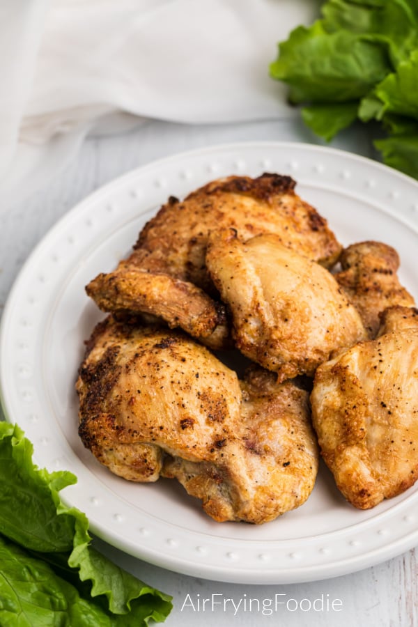 Air Fryer Chicken Thighs fully cooked and seasoned and served on a white plate.