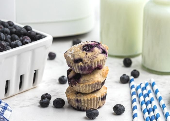 Stack of three muffin with fresh blueberries and milk, in front of the air fryer. 