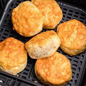 Golden fluffy biscuits stacked in the air fryer basket.