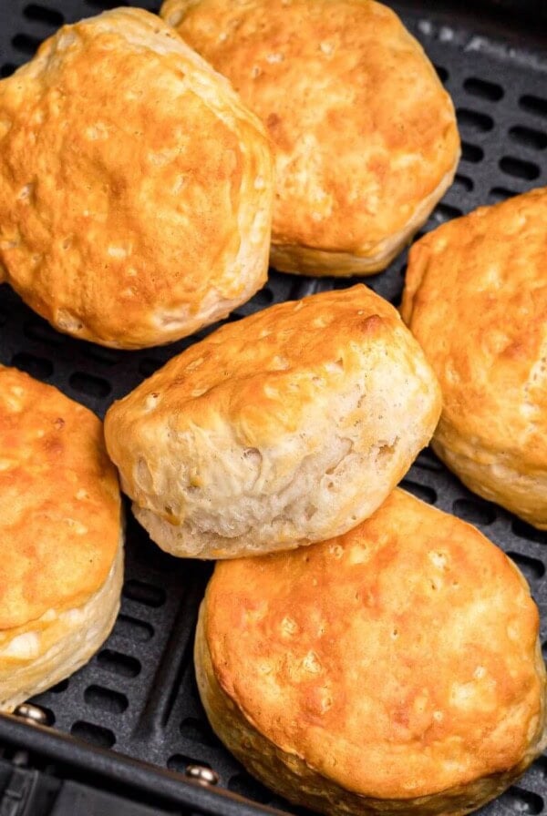 Golden fluffy biscuits stacked in the air fryer basket.